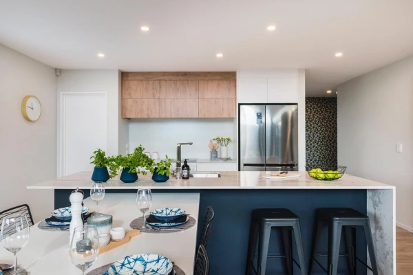 Dark kitchen island with timber cupboards, pendant lights and fresh flowers.