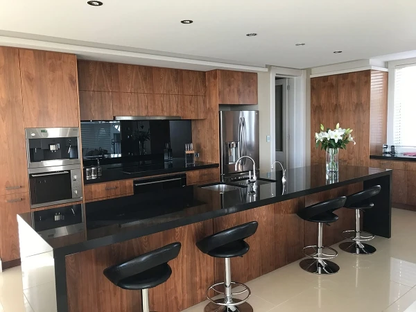 Dark kitchen island with timber cabinetry and bar stools.